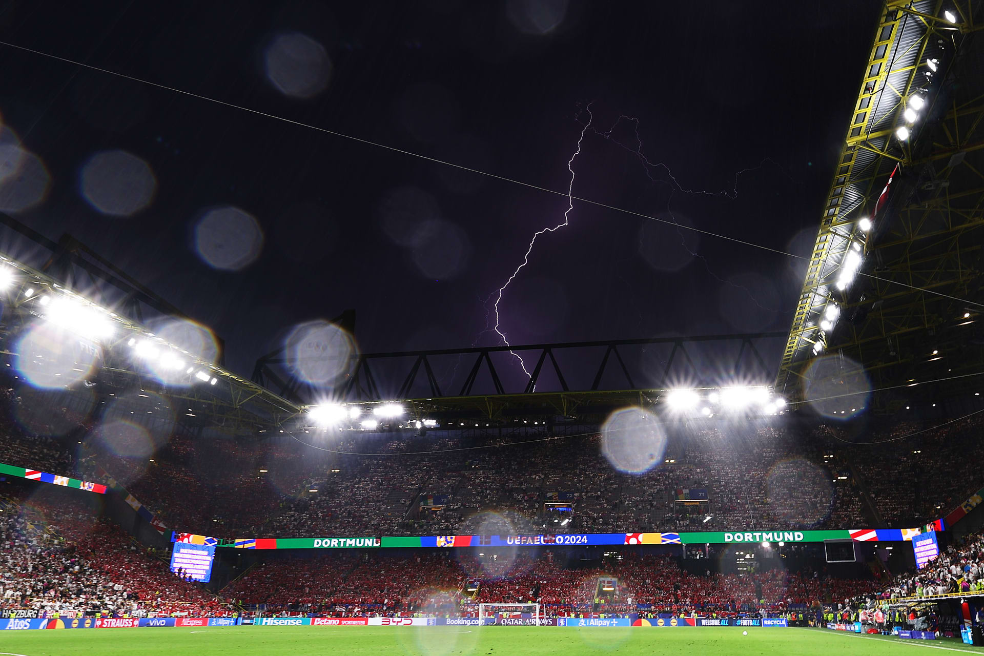 "البرق" يظهر في سماء ملعب مباراة ألمانيا والدنمارك.. ومشجعان يرقصان تحت مياه الأمطار